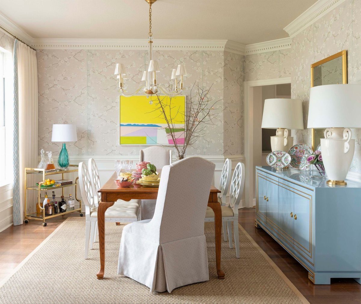 Dining room with a wooden table, blue sideboard, and yellow abstract wall art.