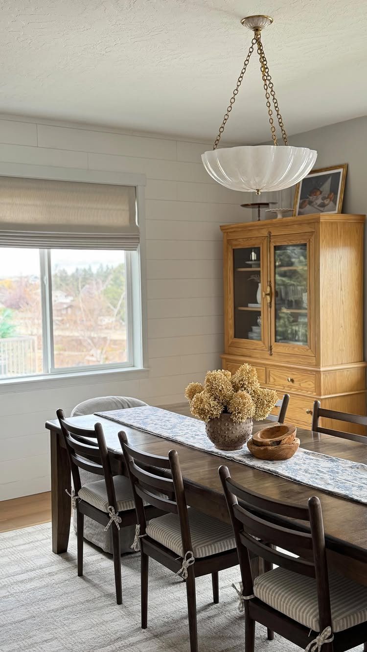 Dining room with a white bowl chandelier and dark wood furniture.