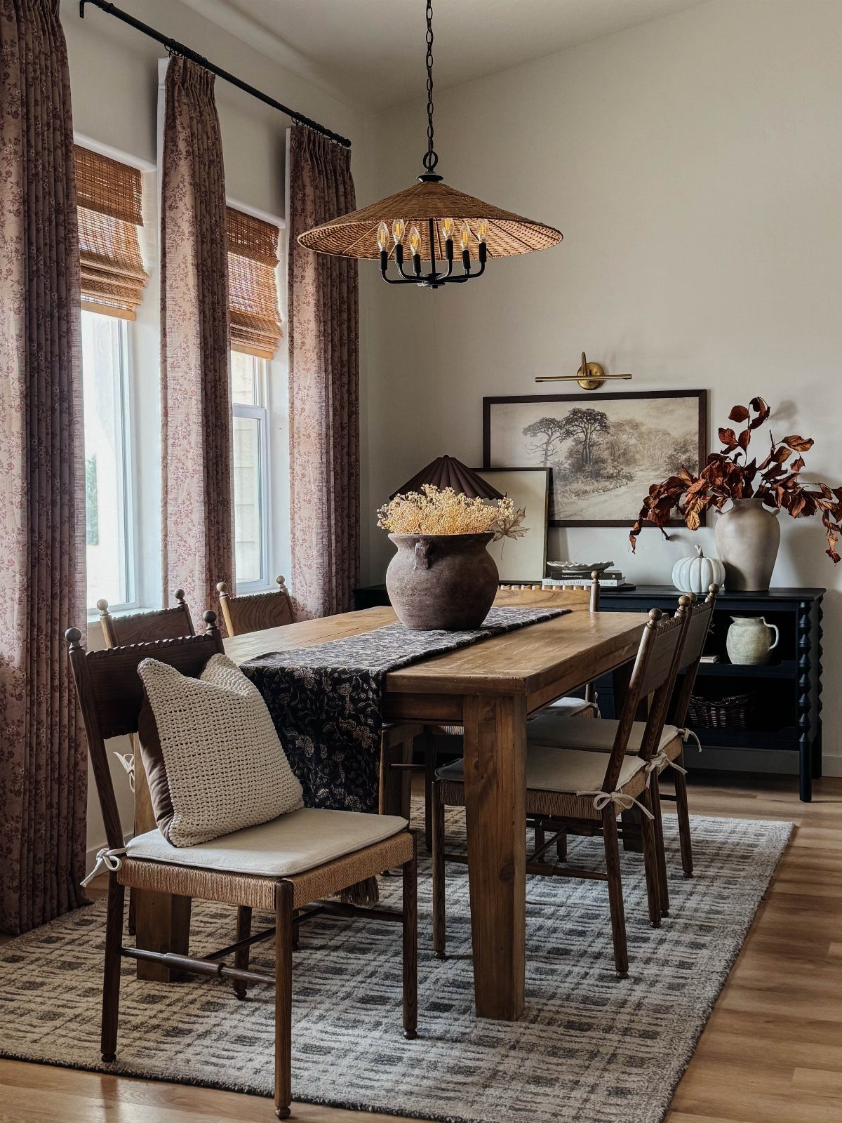 Wooden dining table featuring a large handcrafted ceramic pot with dried flowers.