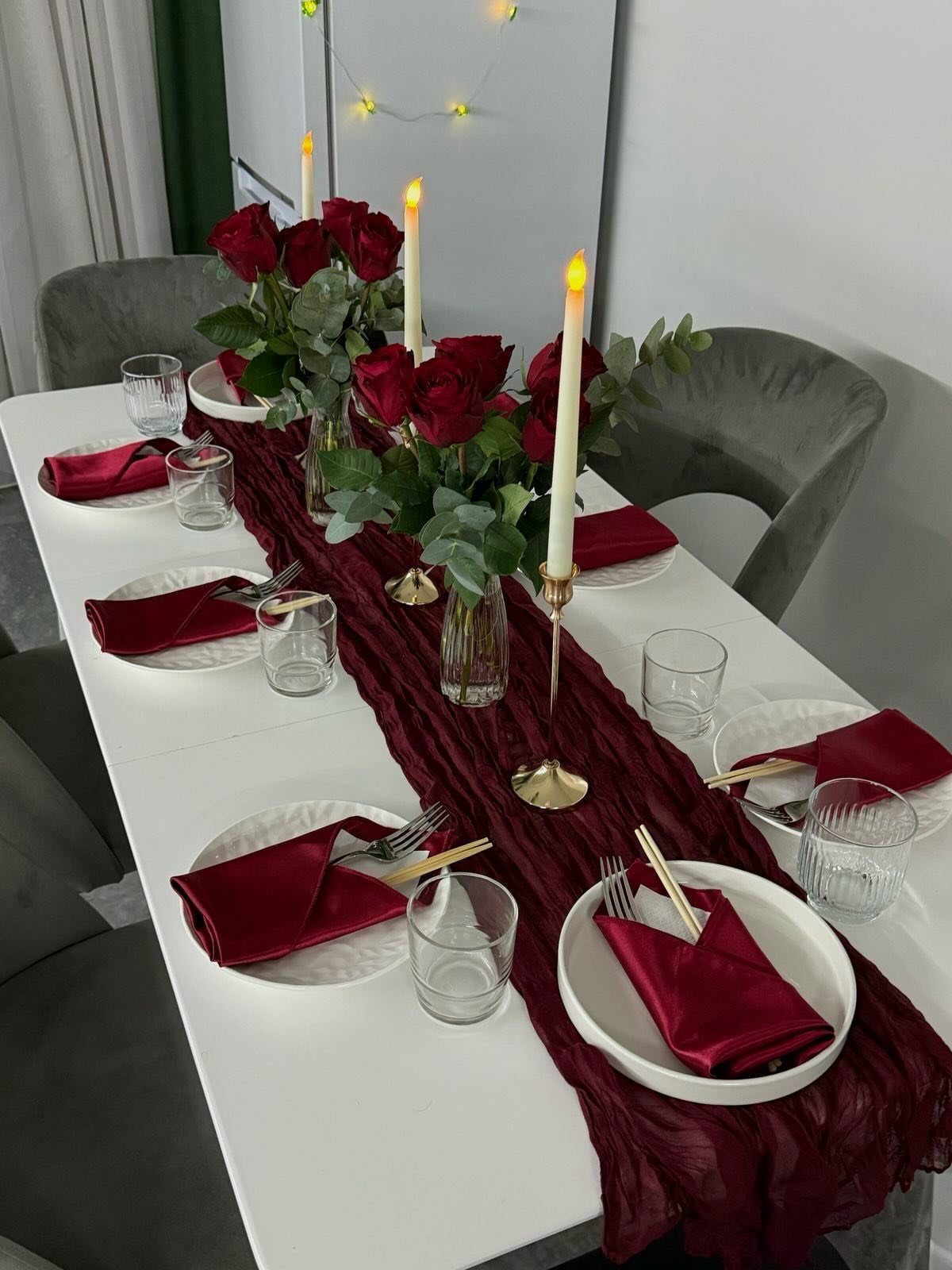 Burgundy fabric table runner with red roses and white candles on white table