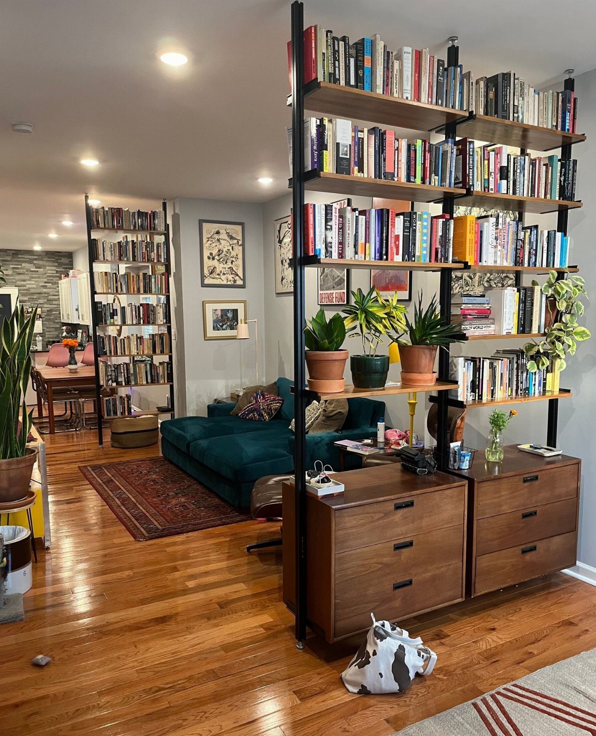 Wooden bookshelf with black metal frames positioned perpendicular to the wall as a divider.