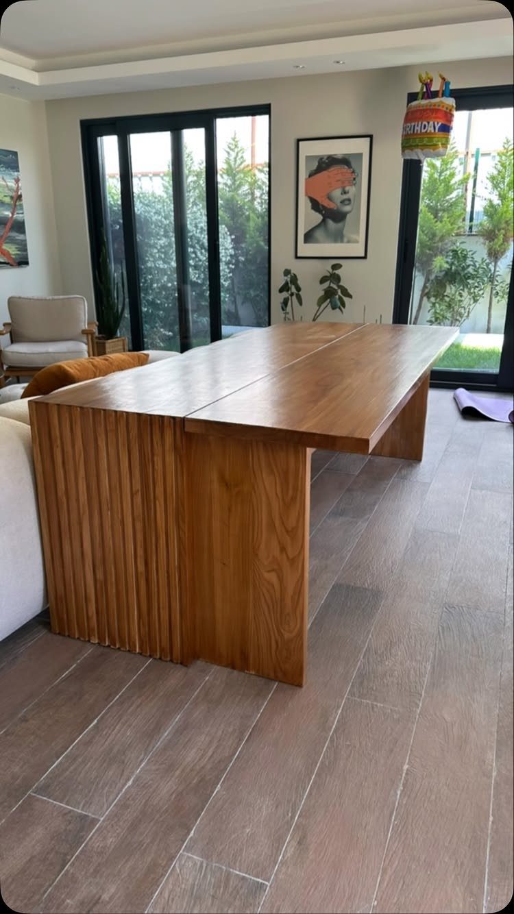 Long wooden dining table with fluted base in a bright modern living room
