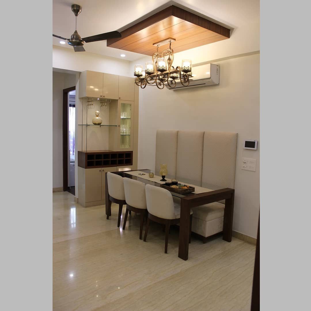 Rectangular wooden dining table with a white upholstered bench seat against a wall.