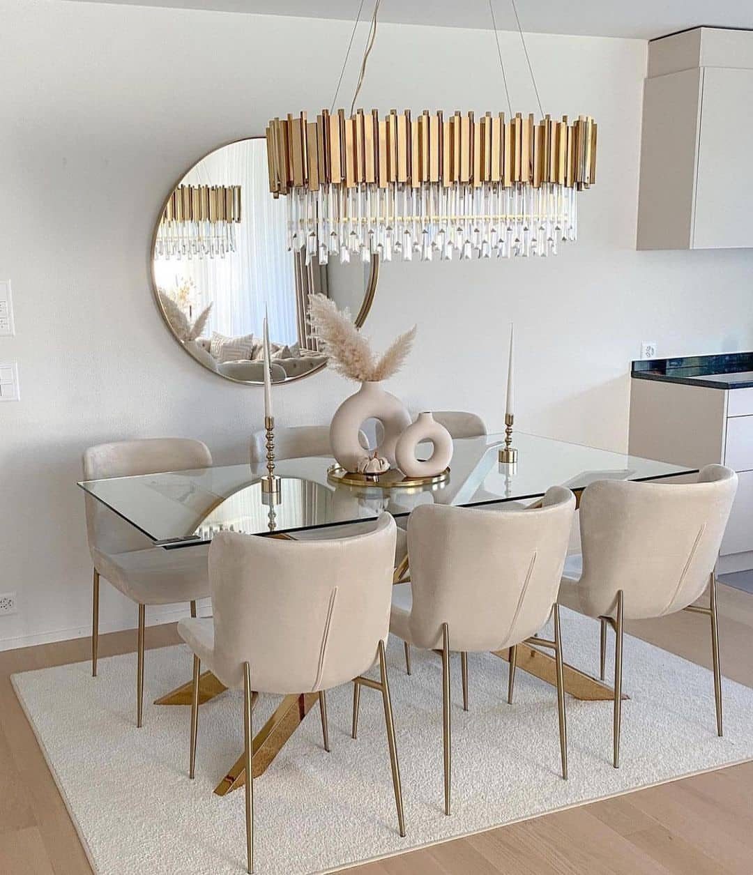 Glass dining table with beige chairs and gold chandelier in a bright room