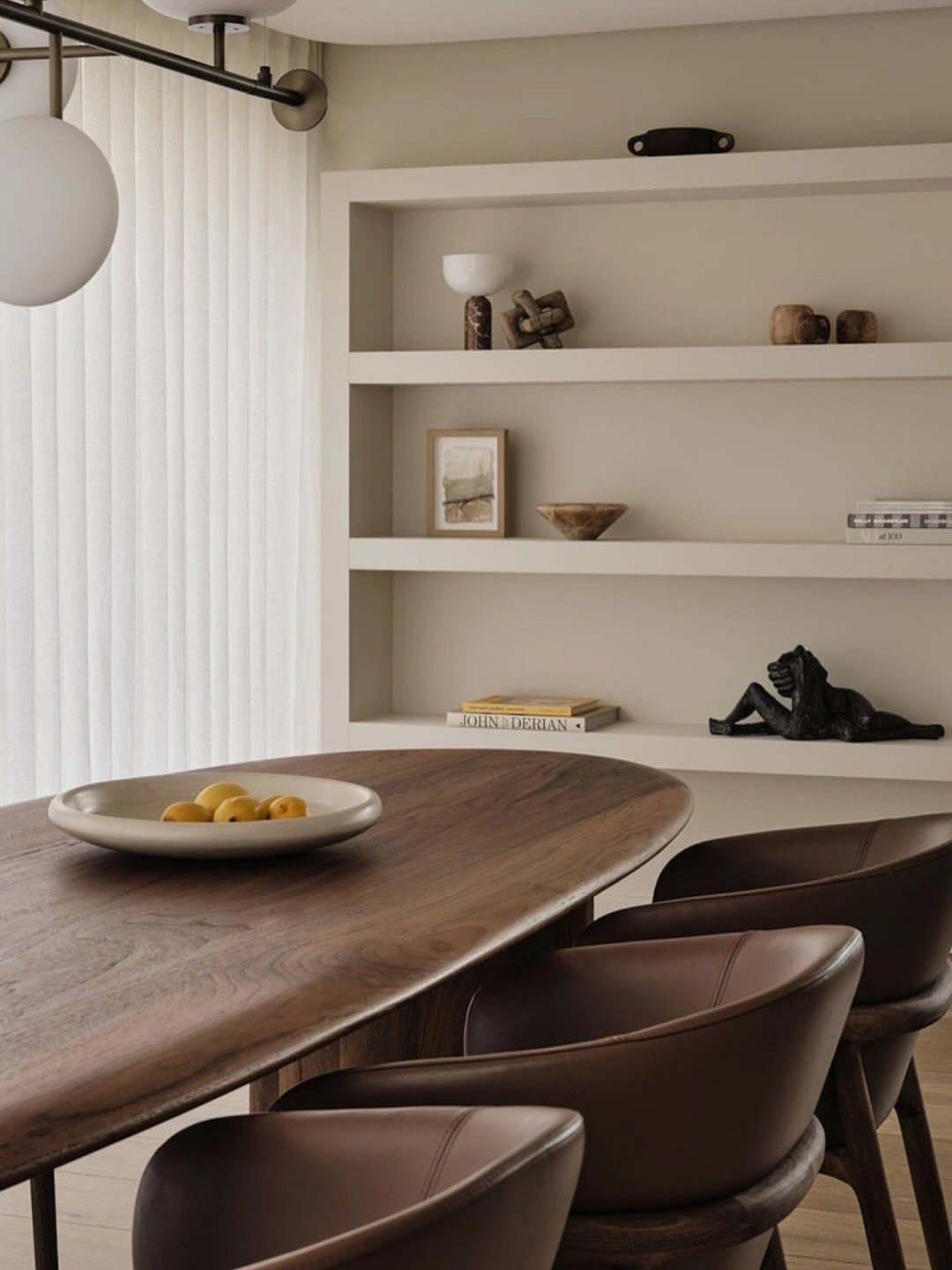 Oval wooden dining table and brown leather chairs in a neutral beige room