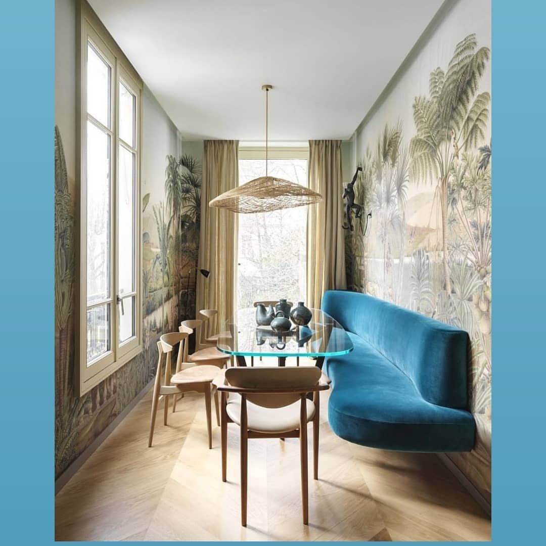 Narrow glass dining table with blue velvet banquette in a slim tropical room