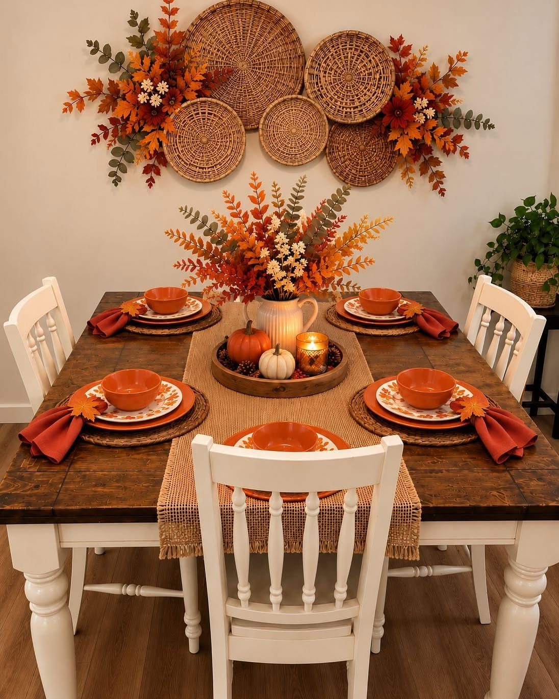 Fall dining table with orange place settings and a textured burlap table runner.