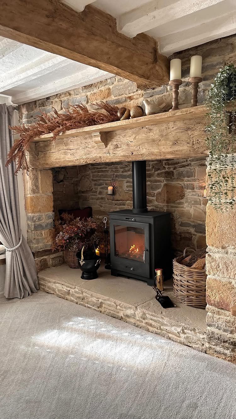 Rustic stone fireplace with a wooden mantel decorated with autumn foliage and candles.