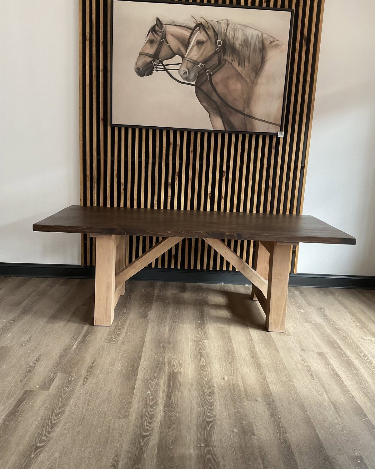 Dark brown wooden table with light wood legs against a slatted wall.