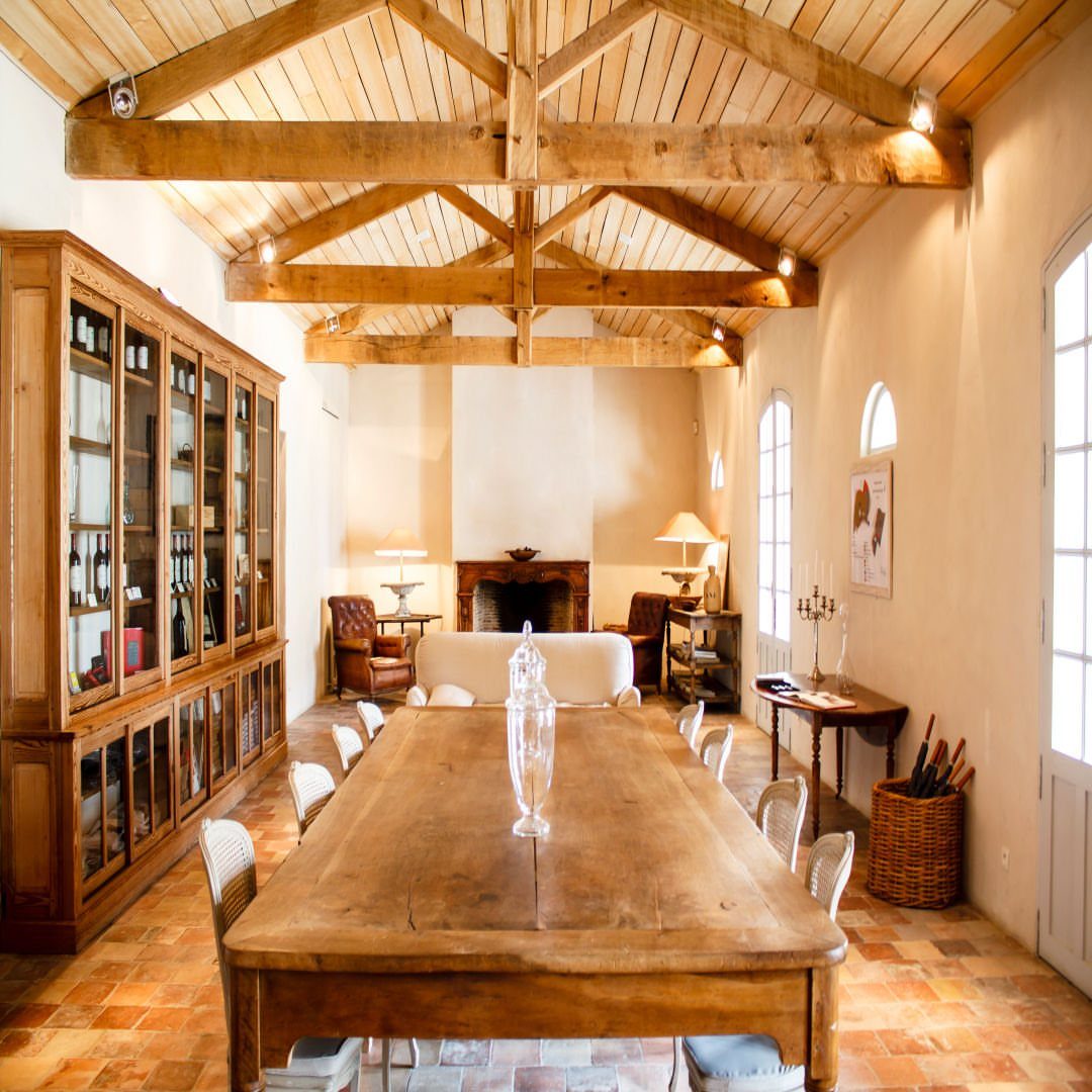 Rustic dining room with a long wooden table and exposed ceiling beams.