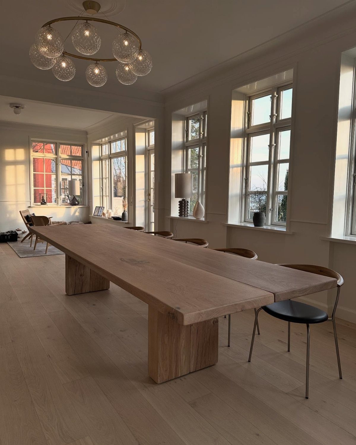 Long light wood dining table with block legs in a bright white room
