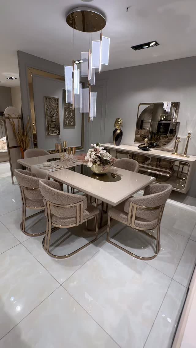 Modern dining room with a white table, gold chairs, and a sleek sideboard.
