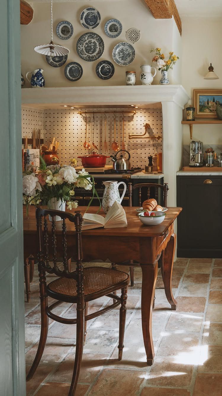 Wooden dining table and cane chair in a rustic kitchen with plate wall decor