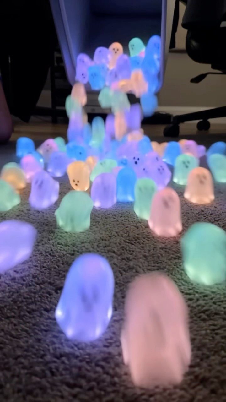 Glowing pastel ghost lights spilling from a container onto a grey carpeted floor.