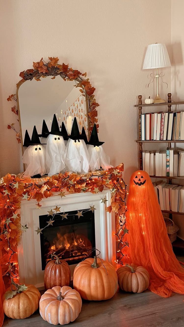 White fireplace mantel decorated with autumn leaves, ghost figures, and orange pumpkins.