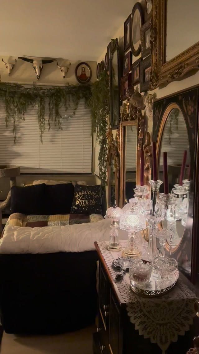 Darkly decorated bedroom with ornate mirrors, crystal candles, and hanging greenery.