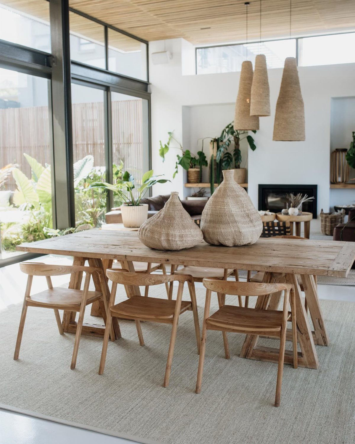 Wooden dining table and chairs centered on a large neutral woven area rug