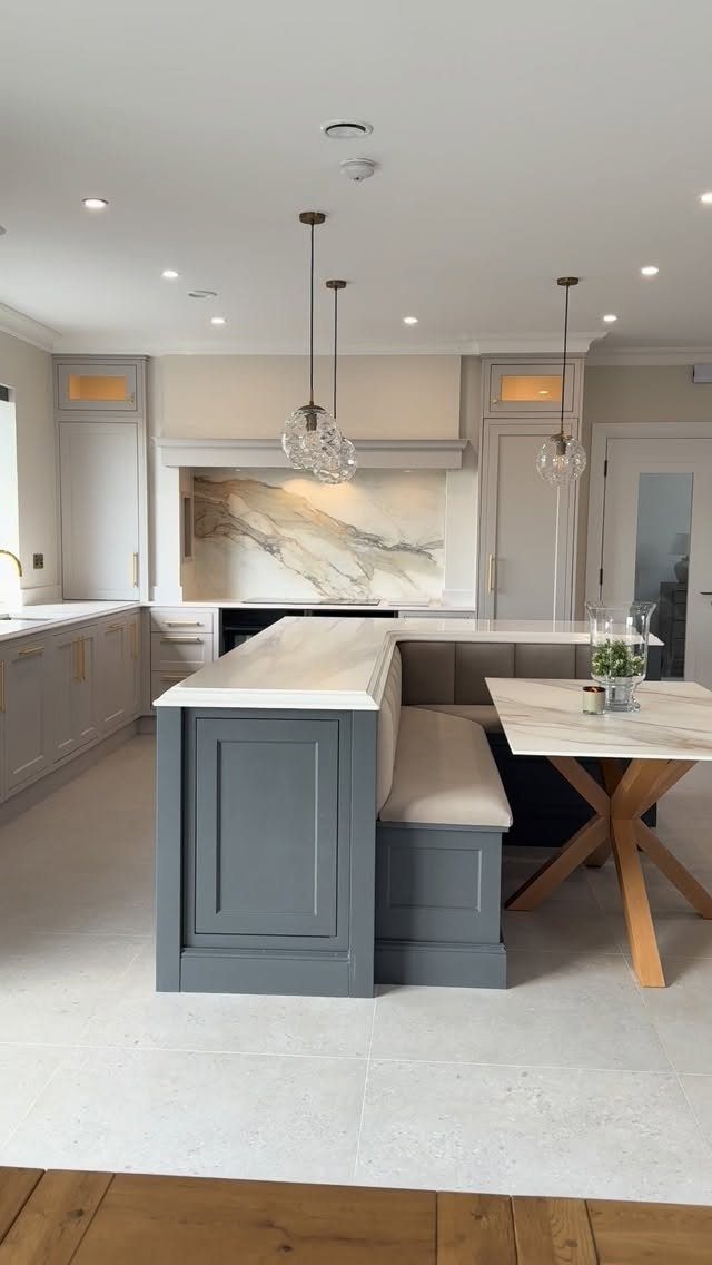 Built-in grey banquette bench with beige cushion and marble dining table in kitchen