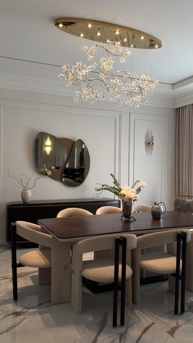 Modern dining room with dark wood table, beige chairs, and branch-like chandelier.