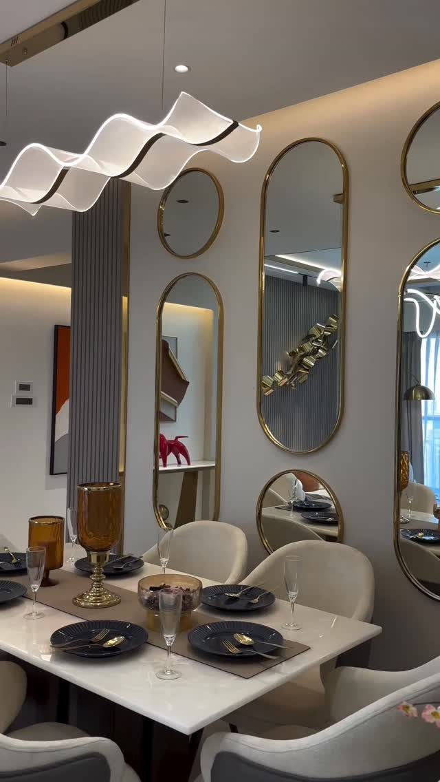 Oval gold-framed mirrors on a white wall above a marble dining table.