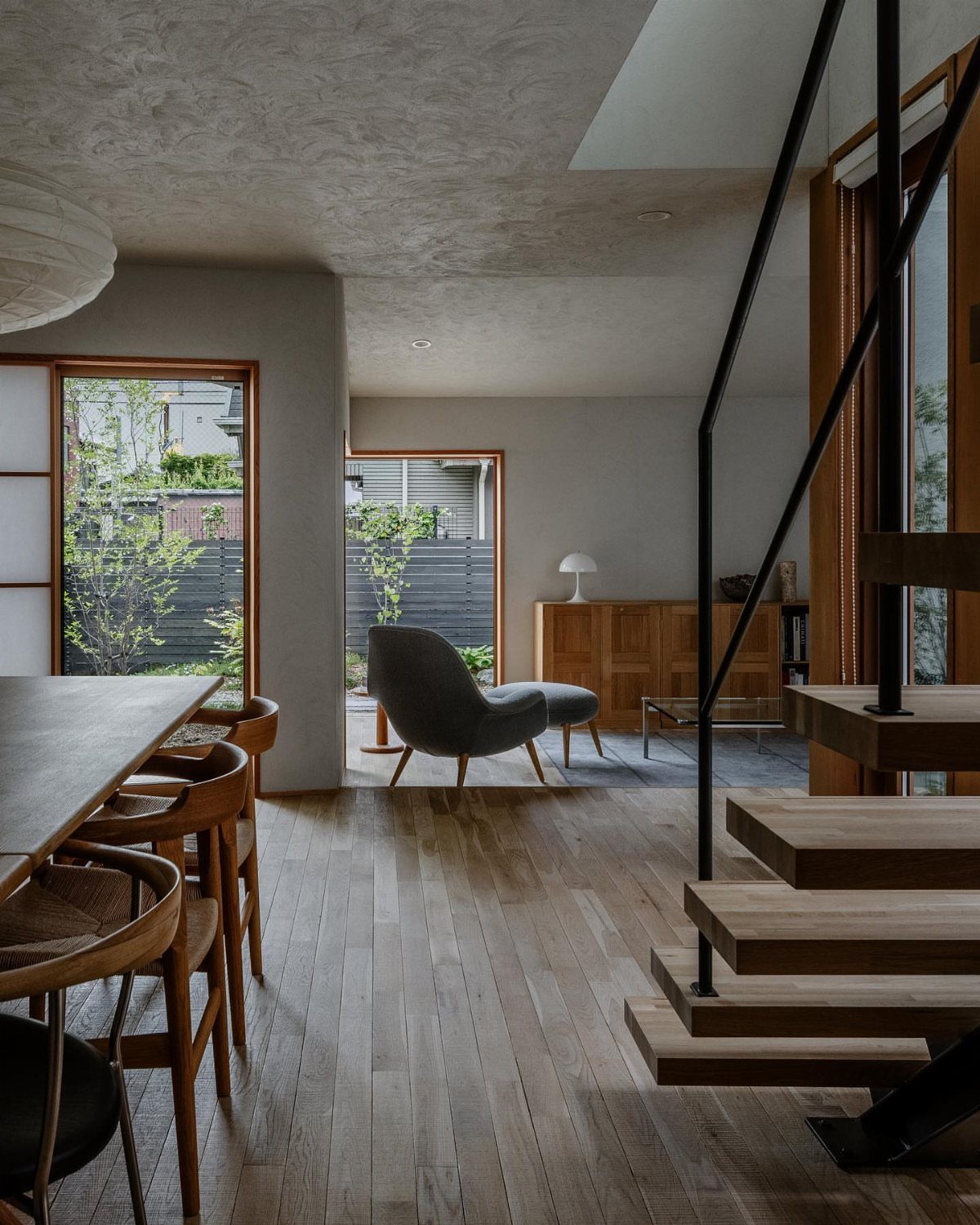 Wooden dining table and chairs in a modern room with concrete ceilings.