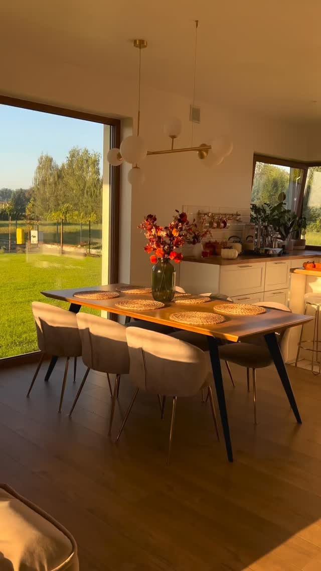 Wooden dining table with beige chairs and woven placemats overlooking a sunny garden