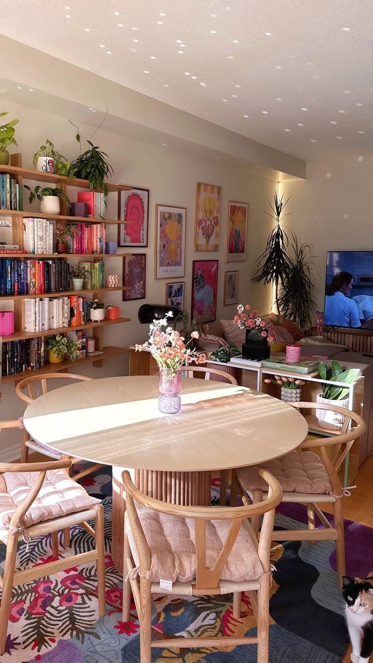 Round wooden dining table and wicker chairs in a room with colorful wall art.