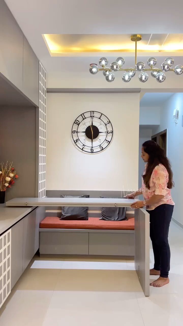 Woman standing by a grey dining table and orange bench in a modern room