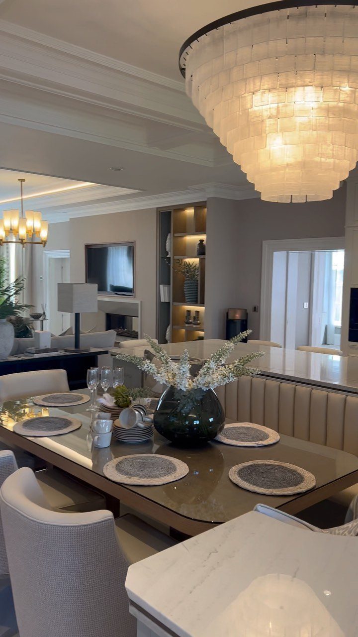 Large tiered white pendant light hanging over a glass dining table in open-concept room