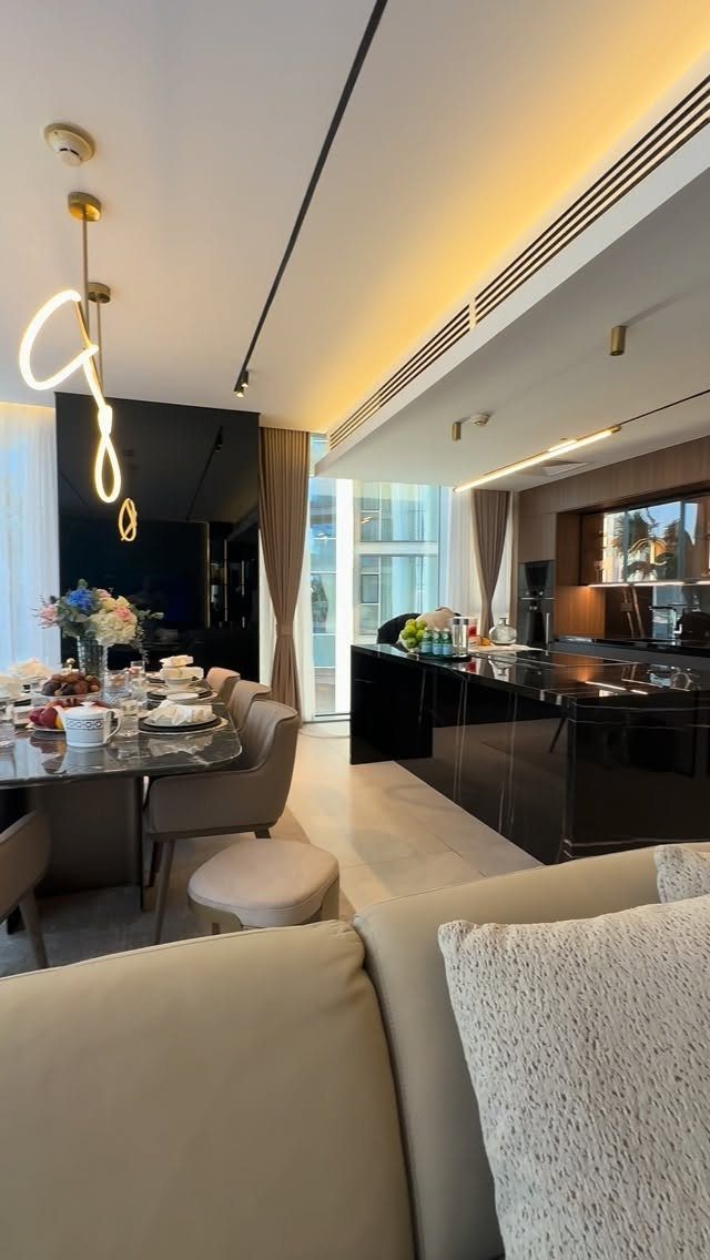Modern open-concept living and dining room with a cohesive beige and black color palette.