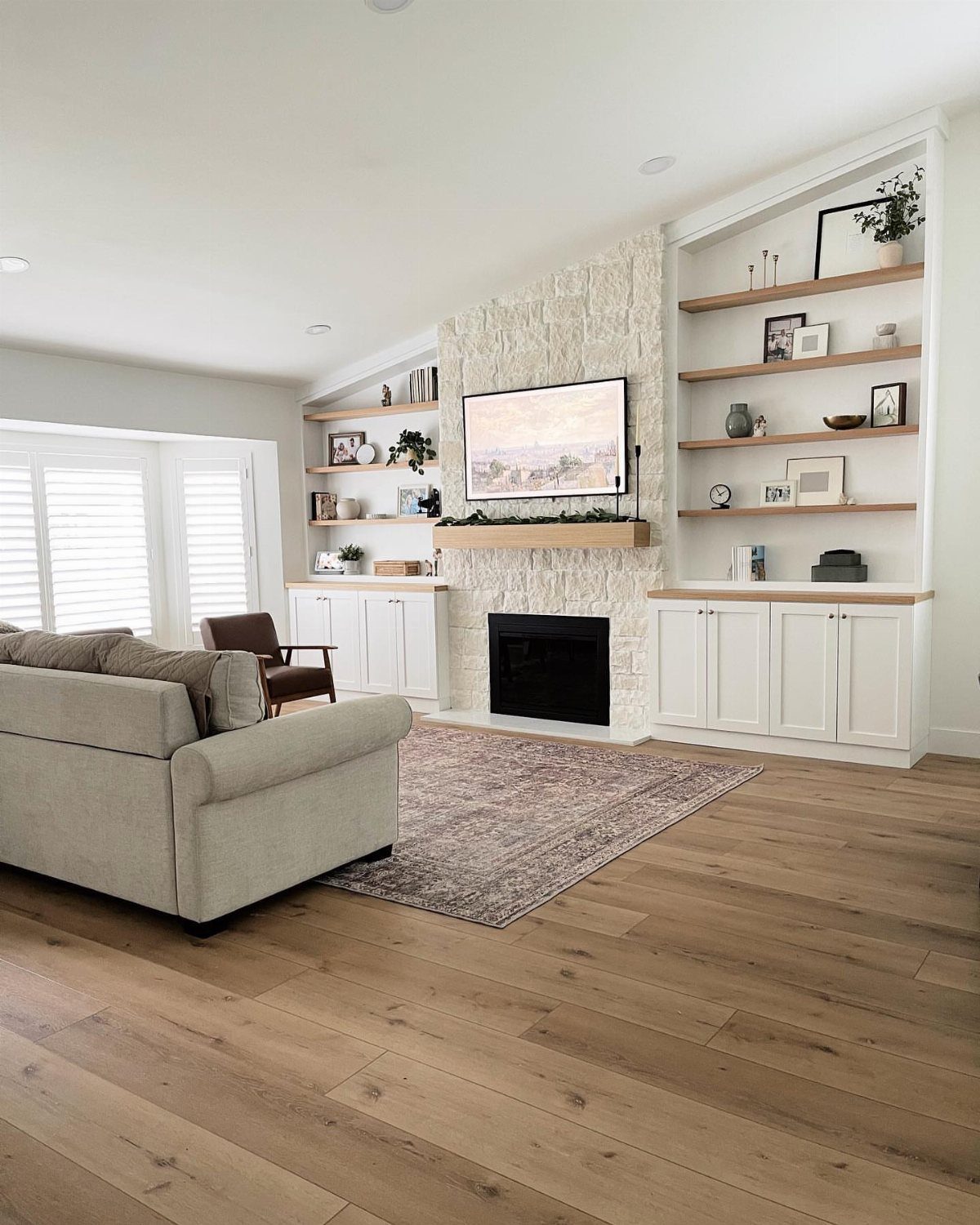 White stone fireplace with wooden mantel and built-in shelves in a modern living room