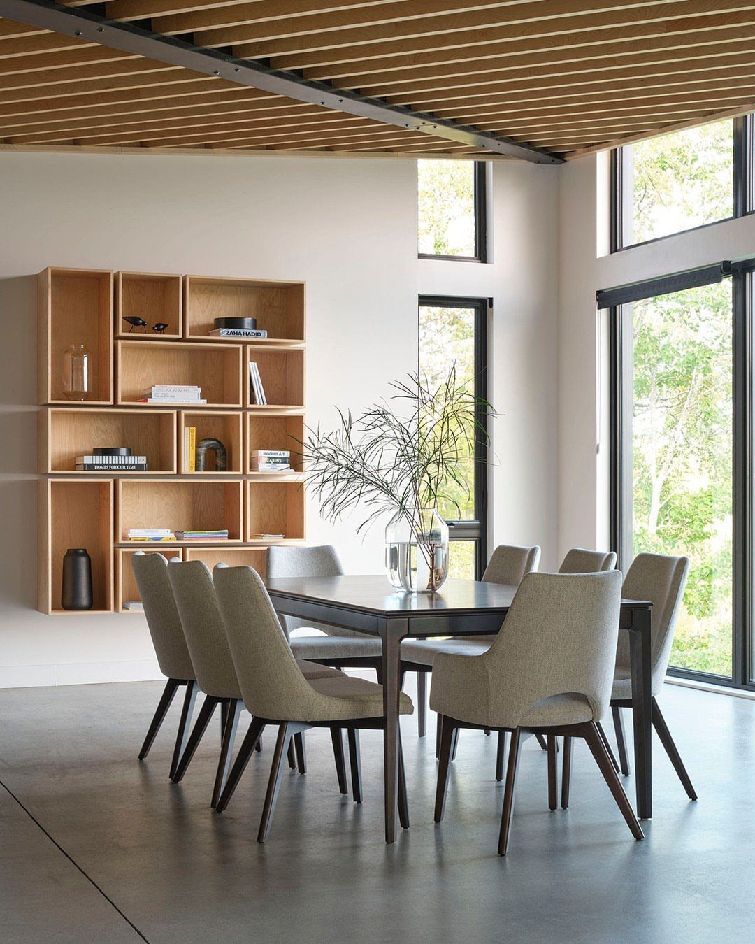 Dining room with a dark wooden table, beige chairs, and modular wood shelving.