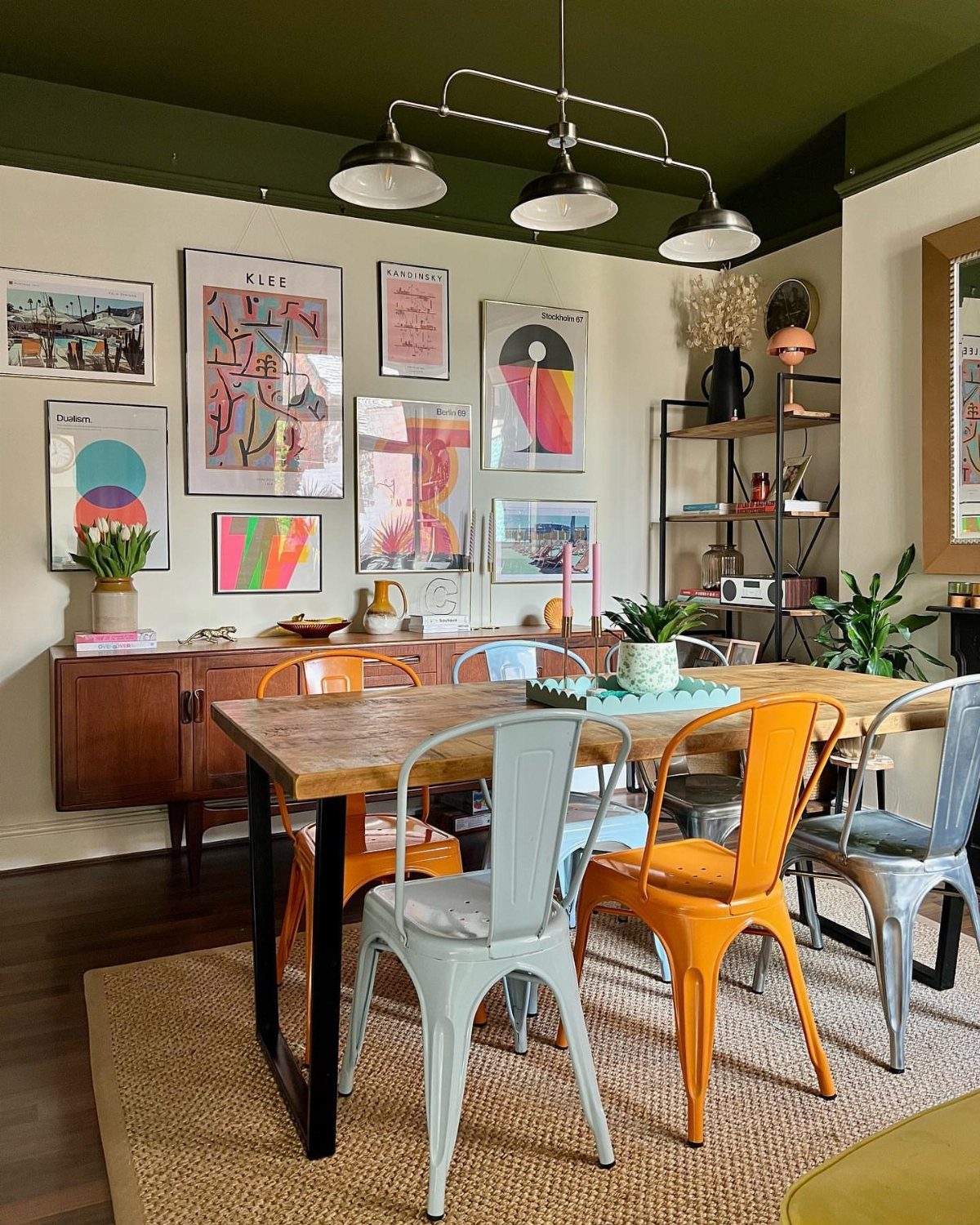Wooden dining table with colorful metal chairs in a mid century modern room