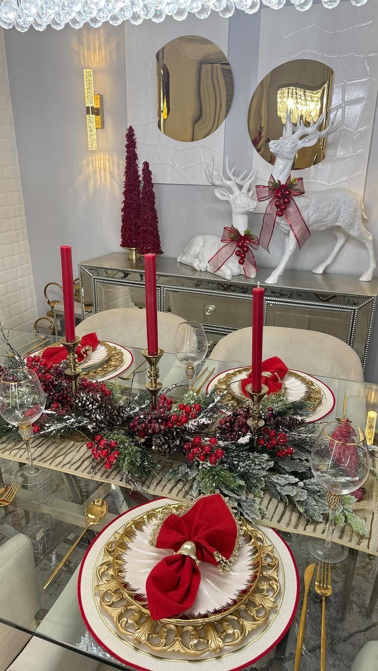Christmas dining table setting with red candles, gold plates, and festive greenery runner.