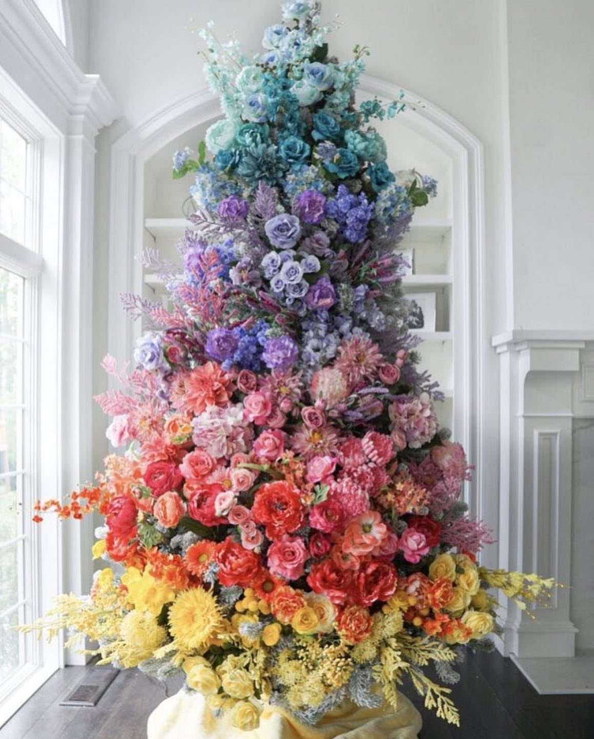 Rainbow floral Christmas tree in a bright white modern living room setting.