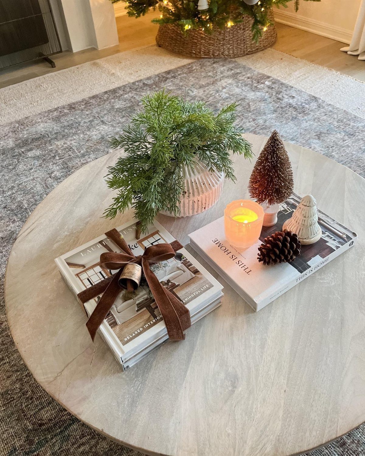 Festive coffee table decor with a small evergreen, candle, and ribboned books.