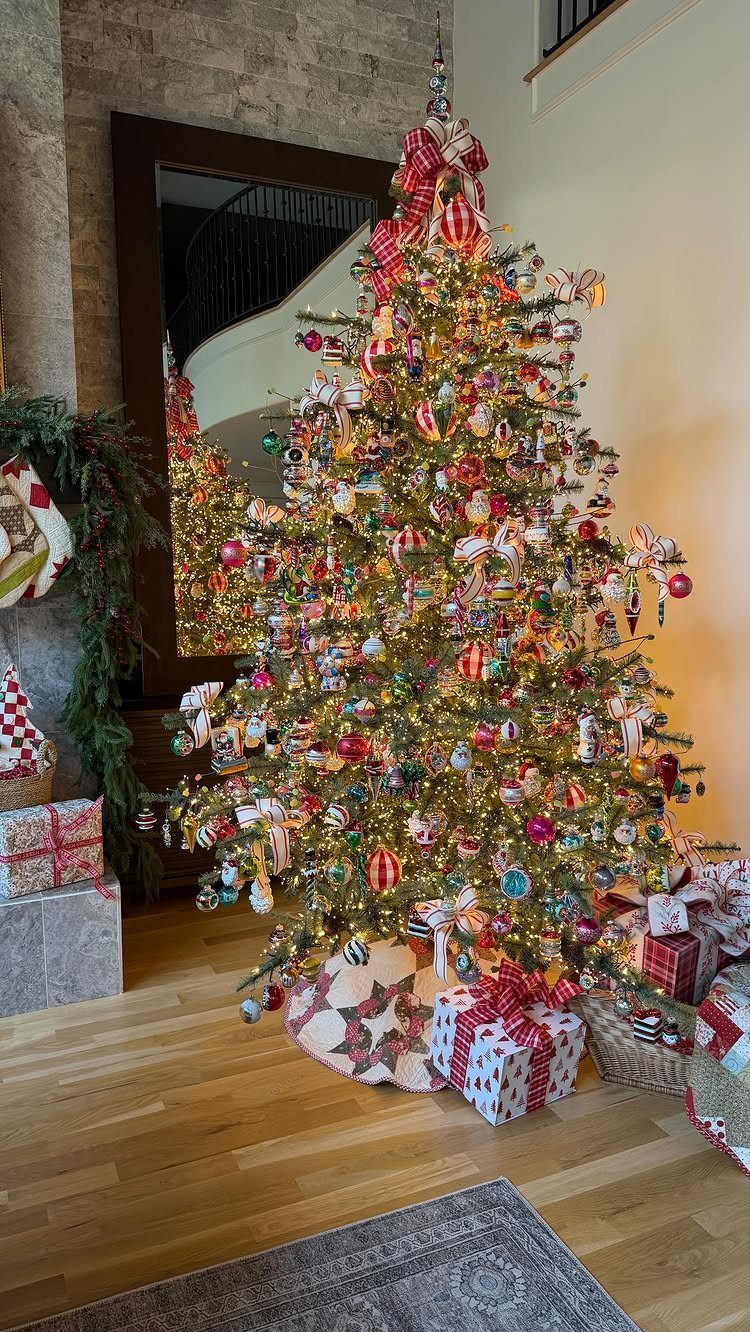 Fully decorated Christmas tree with colorful ornaments and wrapped gifts on wood floor