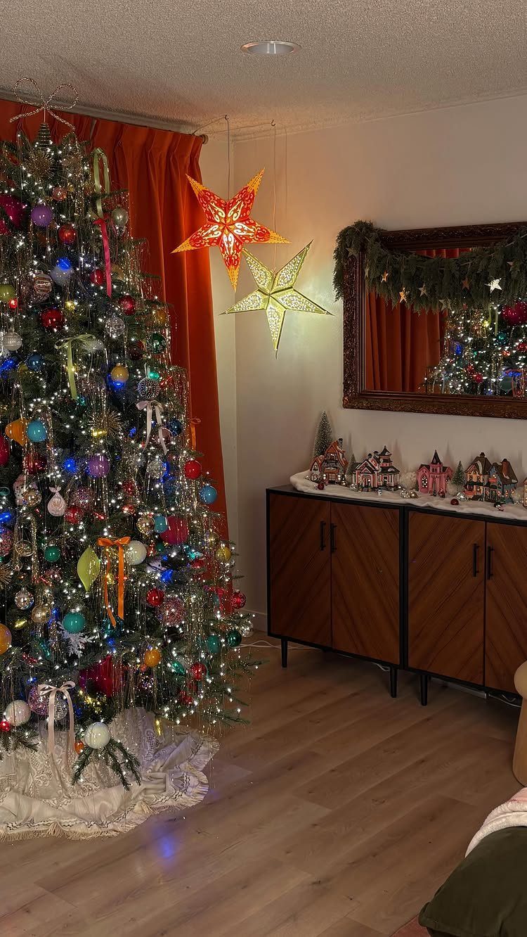 Decorated Christmas tree next to a console table with a miniature holiday village.