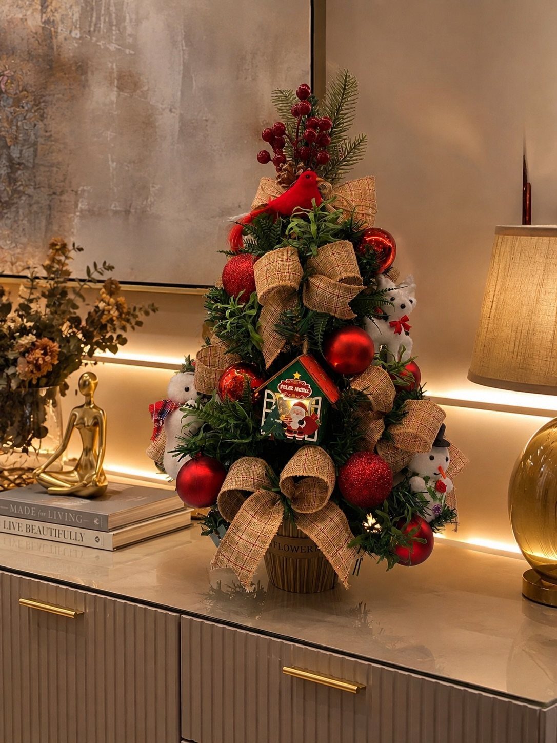 Small decorated Christmas tree with red ornaments and burlap bows on a console table.