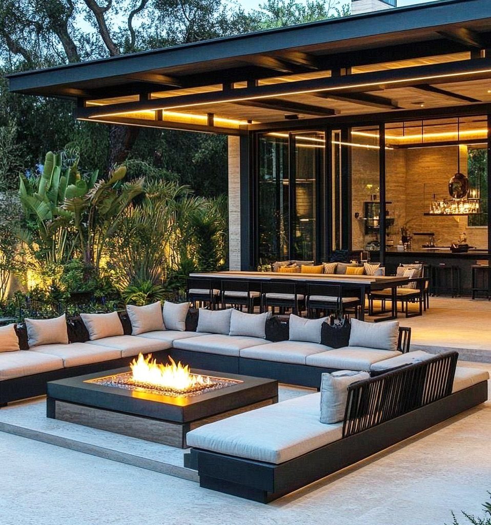 Outdoor patio with a fire pit and dining area next to glass doors.