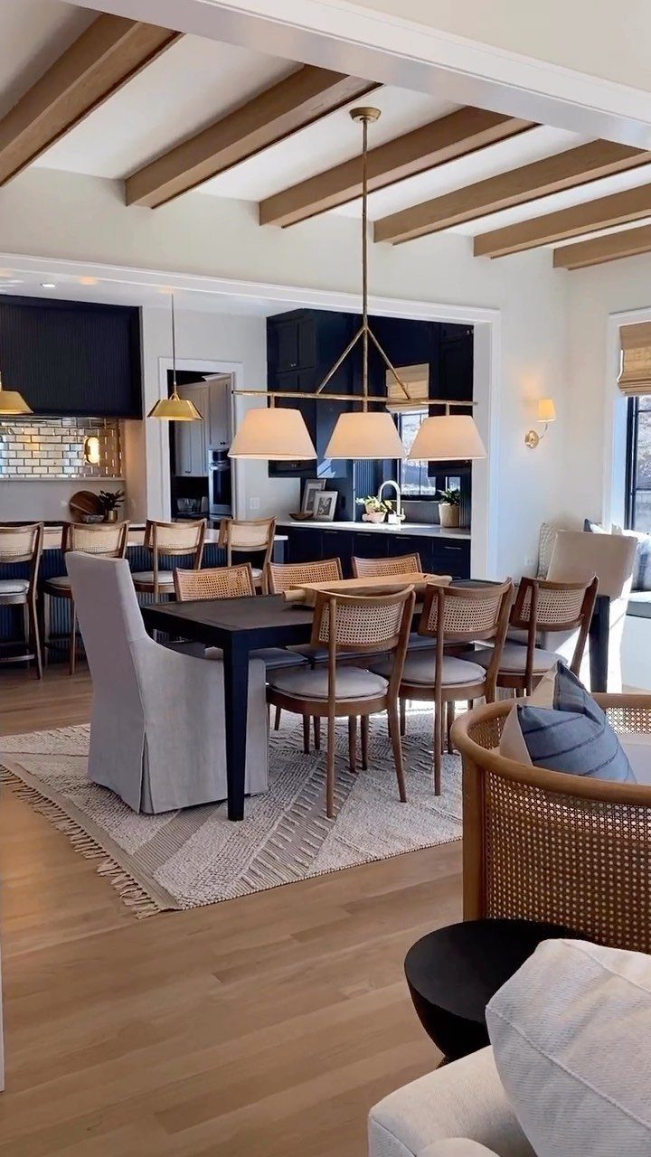 Gold linear chandelier with white shades hanging over a modern black dining table.