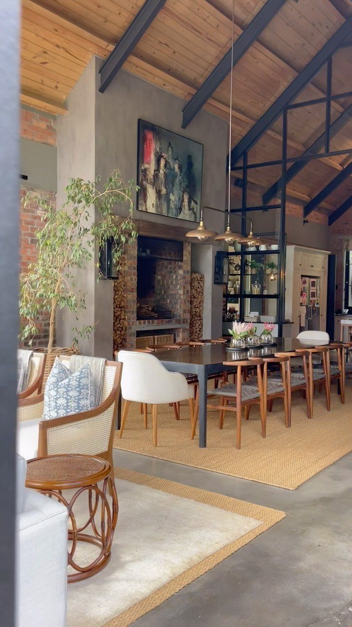 Linear gold pendant lights hanging over a modern dining table in an industrial room.