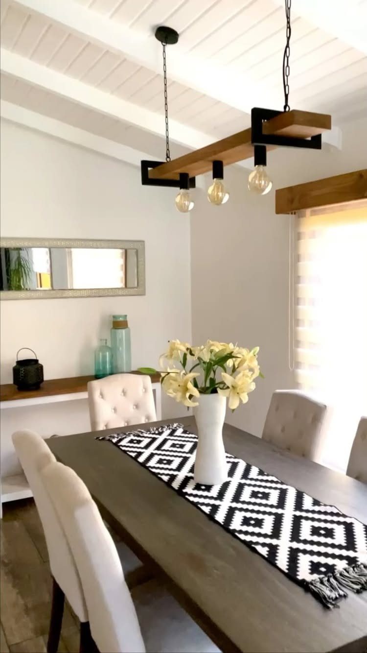 Modern industrial light fixture with exposed bulbs over a wooden dining table.