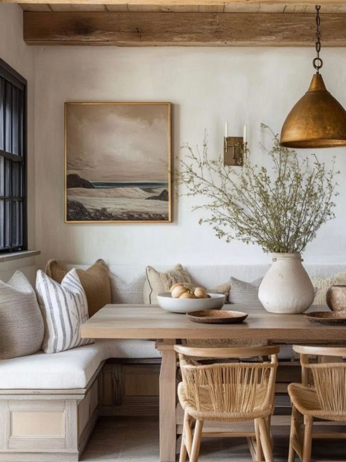 White L-shaped banquette seating with neutral pillows and a light wood dining table.