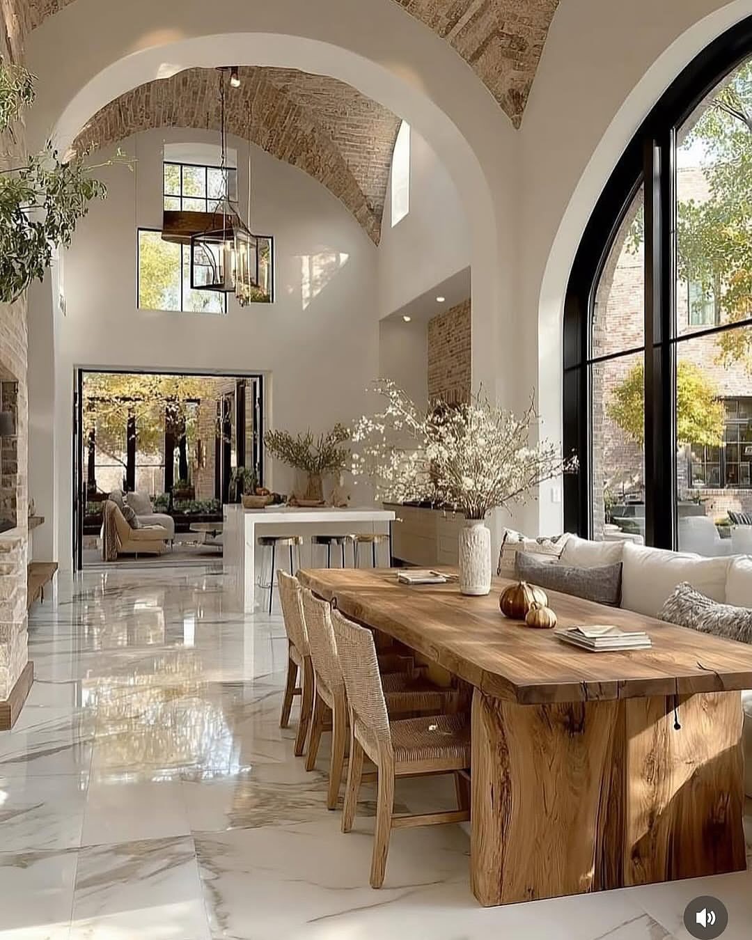 Live-edge wooden dining table with woven chairs in a bright, neutral white room.