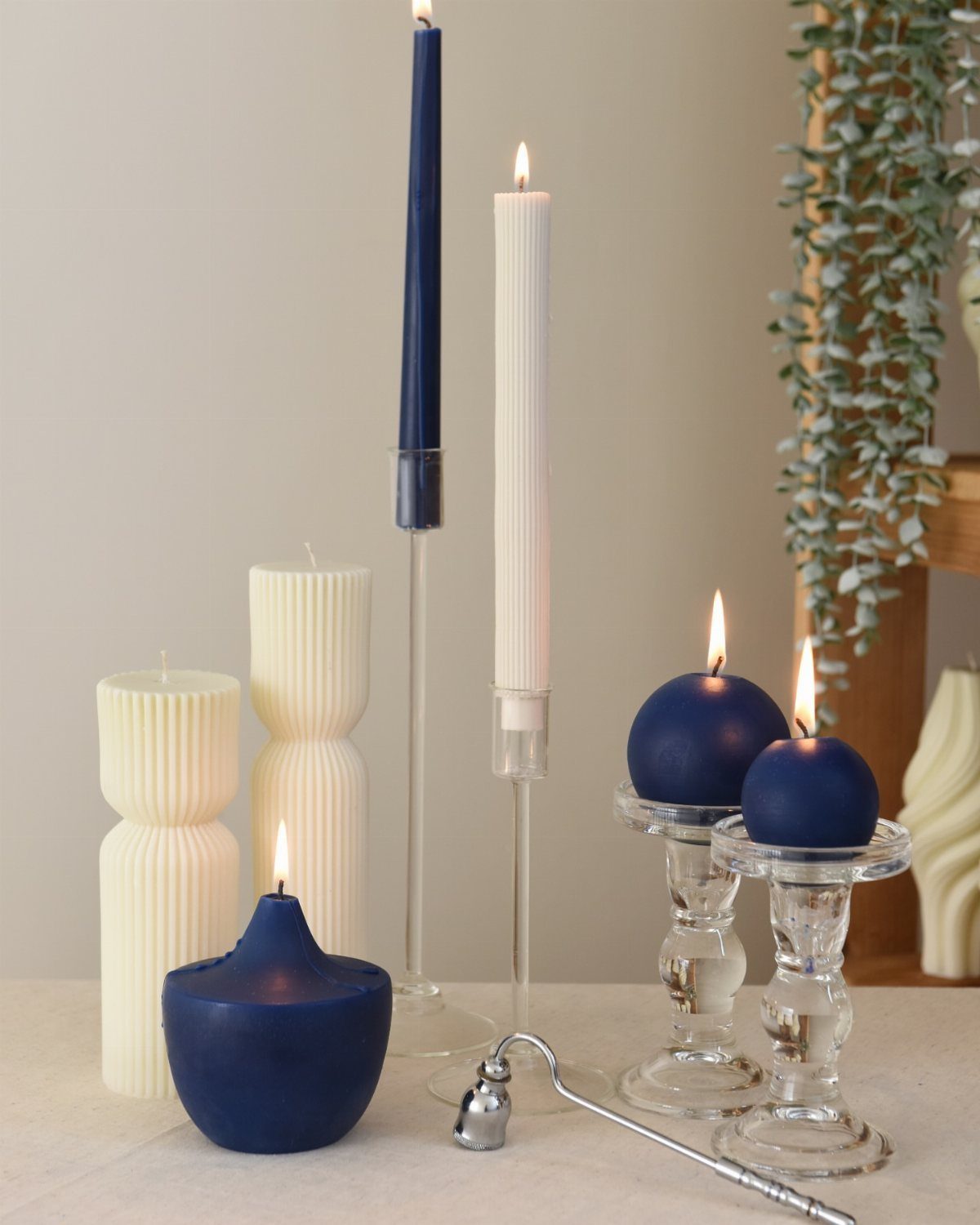 Navy blue and cream candles of various shapes and sizes lit on a table.