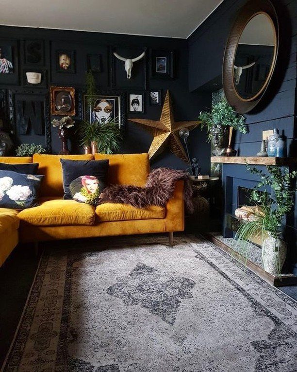 Mustard yellow velvet sofa against navy blue walls with eclectic fall home decor.