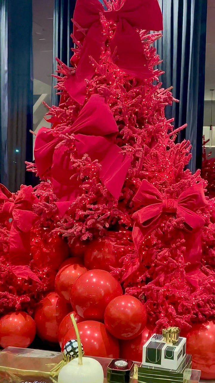 Red Christmas tree with large red bows and red ornaments at the base.