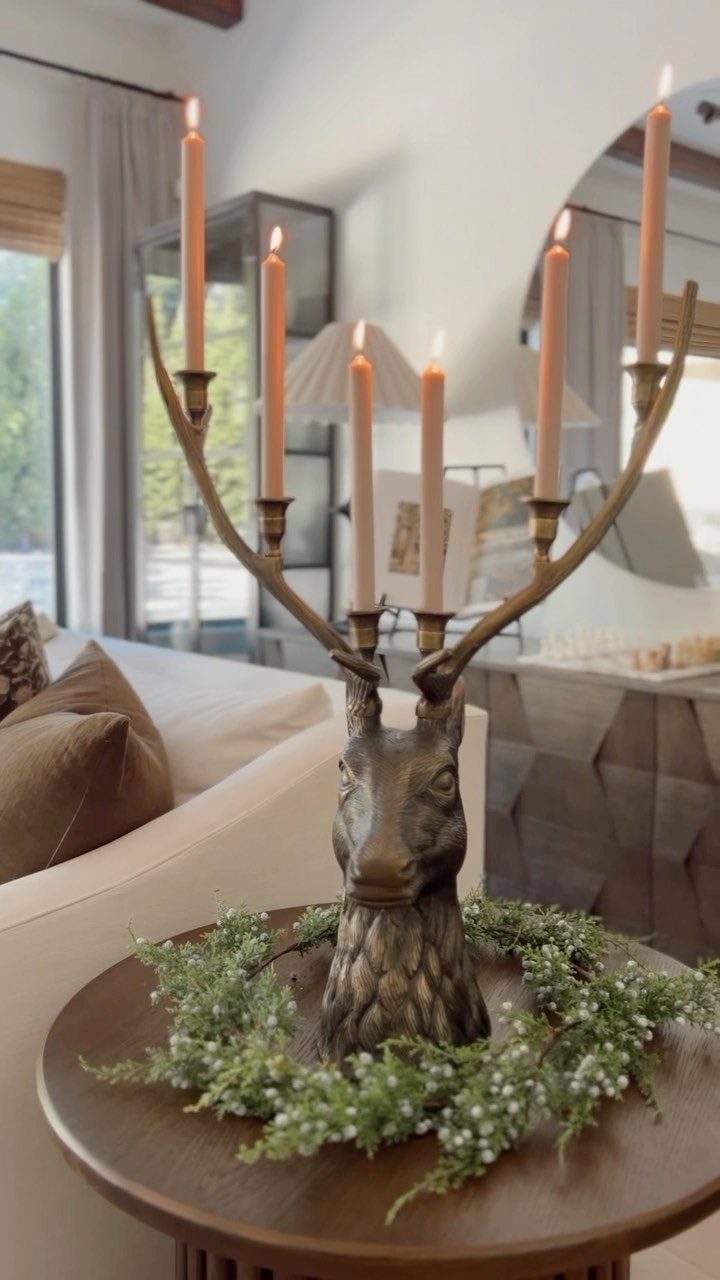 Deer head candelabra with lit candles and pine greenery on a wooden table