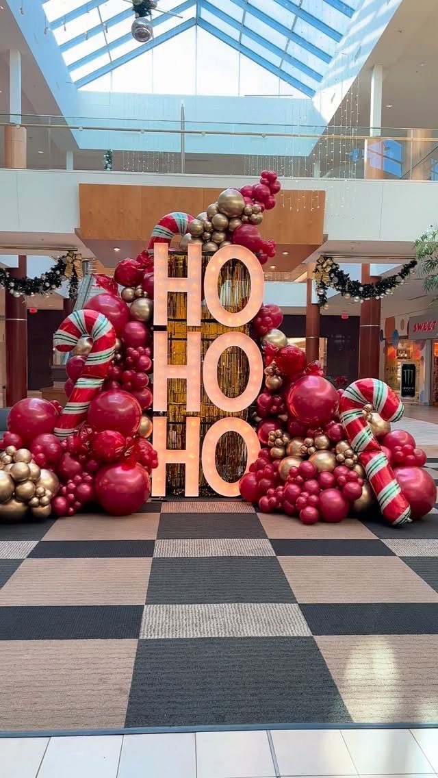 Large light-up HO HO HO marquee letters surrounded by red and gold balloons.